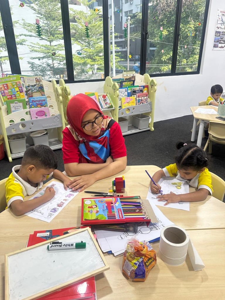 Teacher assisting two young children with tracing and coloring activities in a bright classroom